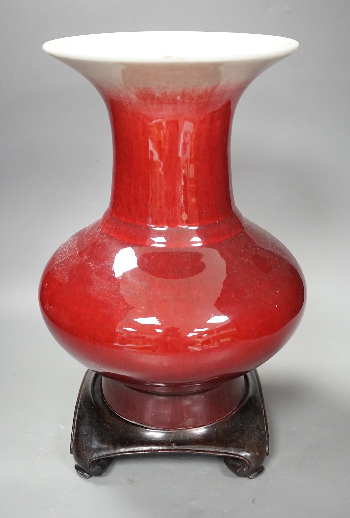 A 19th century Chinese sang de boeuf vase of squat baluster form with everted rim (a.f.), on square hardwood stand, overall 35.5cm high